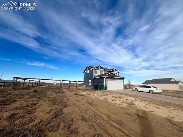 view of front of property with a garage and a rural view