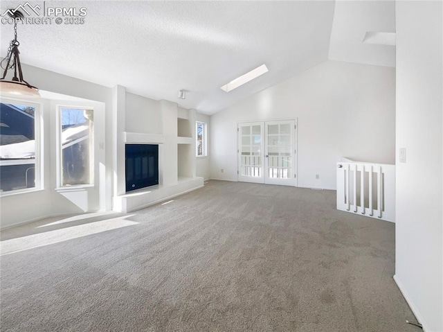 unfurnished living room featuring carpet, a healthy amount of sunlight, a textured ceiling, and a skylight