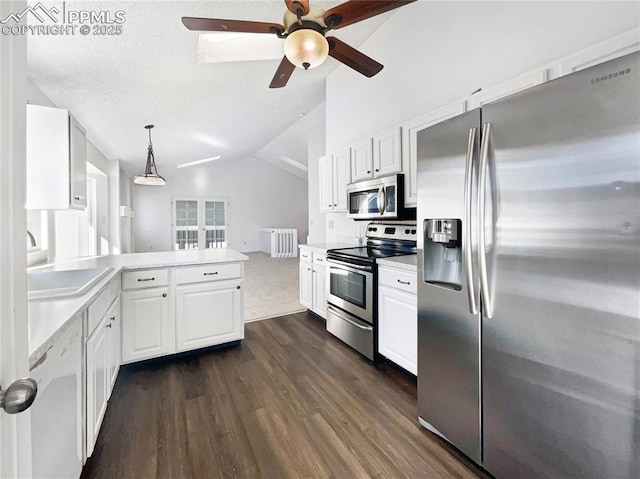 kitchen with radiator, appliances with stainless steel finishes, white cabinets, decorative light fixtures, and vaulted ceiling