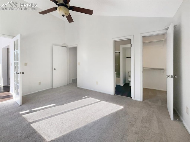 unfurnished bedroom with connected bathroom, a spacious closet, light carpet, a closet, and ceiling fan