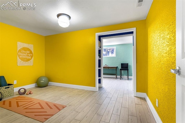 exercise area with hardwood / wood-style floors and baseboard heating