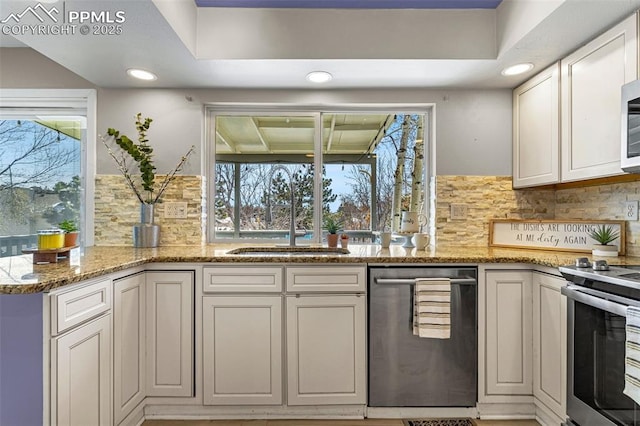 kitchen featuring stone counters, appliances with stainless steel finishes, tasteful backsplash, white cabinetry, and sink