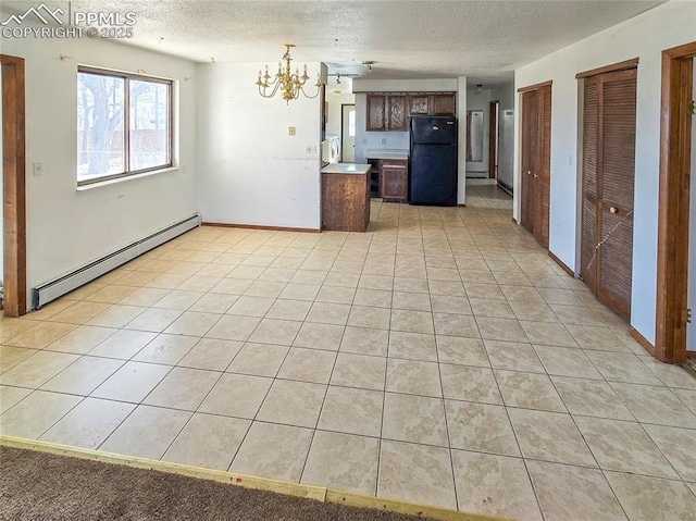 kitchen with light tile patterned floors, a baseboard heating unit, black fridge, decorative light fixtures, and a chandelier