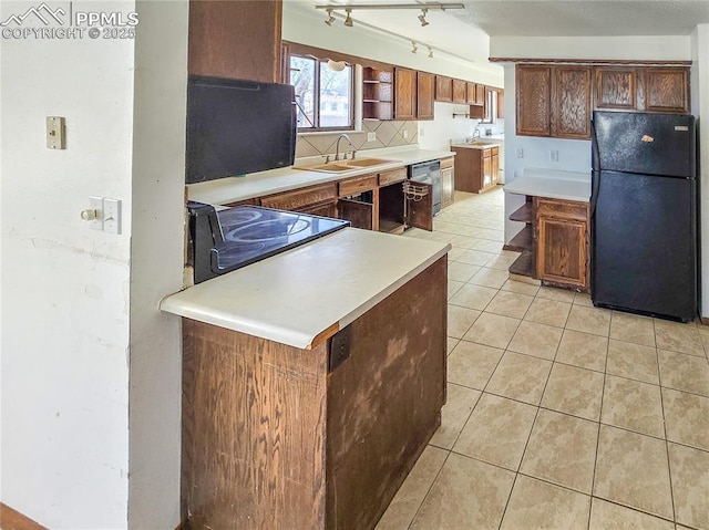 kitchen with sink, dishwashing machine, backsplash, light tile patterned floors, and black fridge