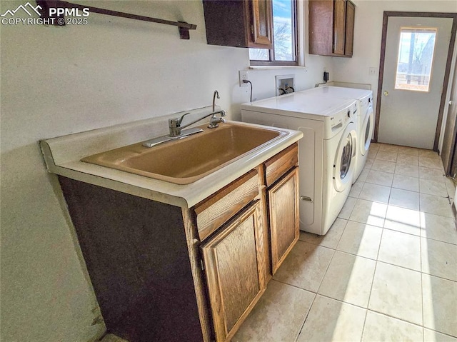 clothes washing area with cabinets, light tile patterned floors, washing machine and dryer, and a wealth of natural light