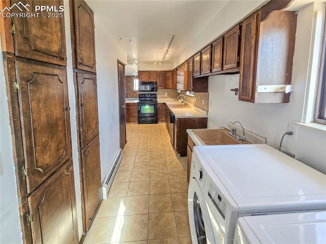 kitchen with a baseboard radiator, sink, washer and clothes dryer, and black appliances