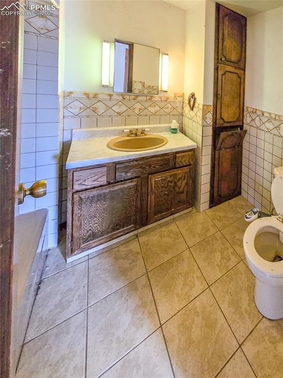 bathroom with tile walls, vanity, tile patterned flooring, and toilet