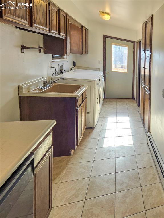 kitchen featuring washing machine and clothes dryer, sink, light tile patterned floors, a baseboard radiator, and black dishwasher