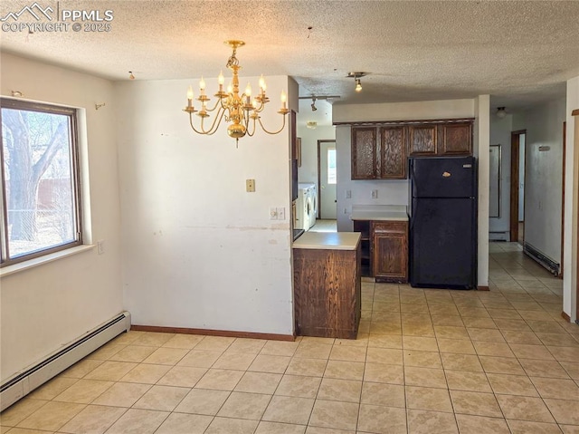 kitchen with black fridge, a chandelier, light tile patterned floors, pendant lighting, and a baseboard heating unit