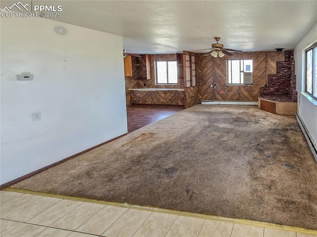 unfurnished living room with baseboard heating, ceiling fan, carpet floors, and a textured ceiling