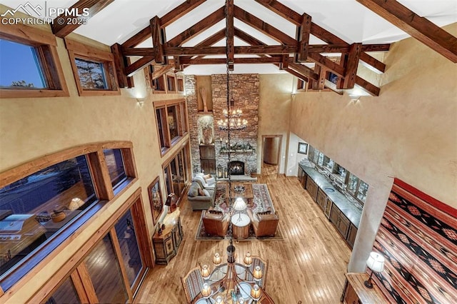 201 Fox Mountain Dr, Woodland Park, CO 80863 - living room featuring a stone fireplace, high vaulted ceiling, a notable chandelier, and beam ceiling