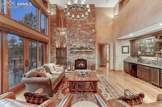 living room with a notable chandelier, a fireplace, and light wood-type flooring