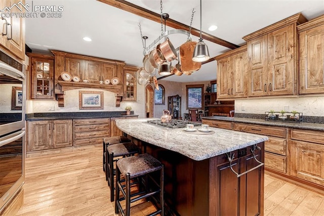 201 Fox Mountain Dr, Woodland Park, CO 80863 - kitchen with appliances with stainless steel finishes, beam ceiling, light hardwood / wood-style floors, a kitchen island, and dark stone counters