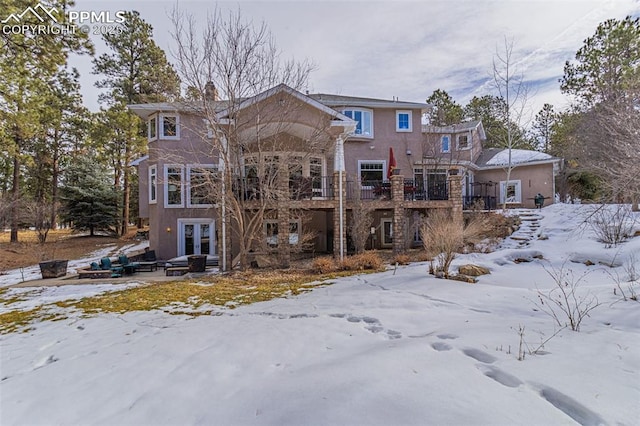 snow covered back of property with french doors