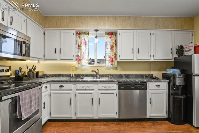 kitchen featuring white cabinetry, appliances with stainless steel finishes, sink, and hanging light fixtures