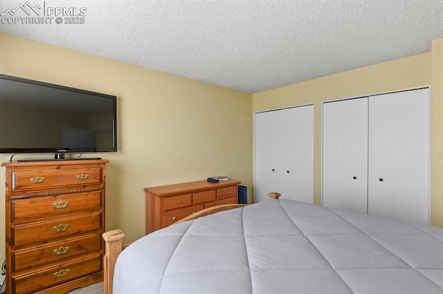 bedroom featuring a textured ceiling and multiple closets