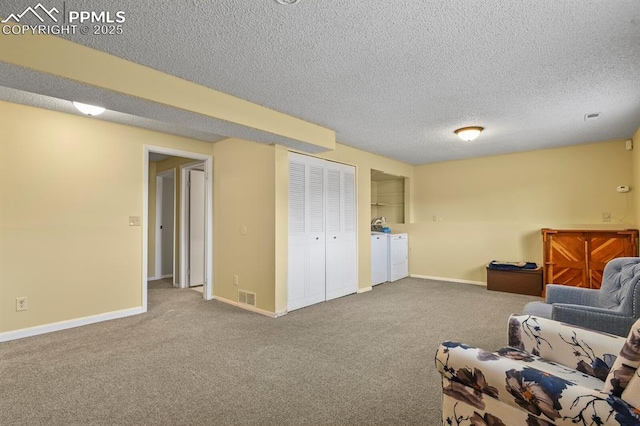 living area featuring carpet floors, washing machine and dryer, and a textured ceiling