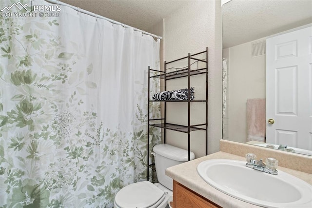 bathroom with vanity, a textured ceiling, and toilet