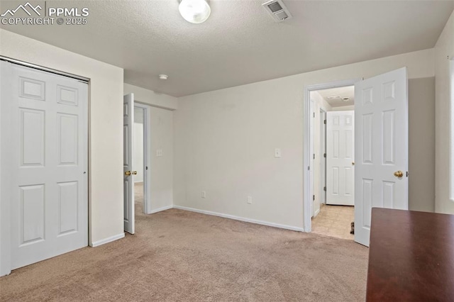 unfurnished bedroom featuring light colored carpet and a textured ceiling