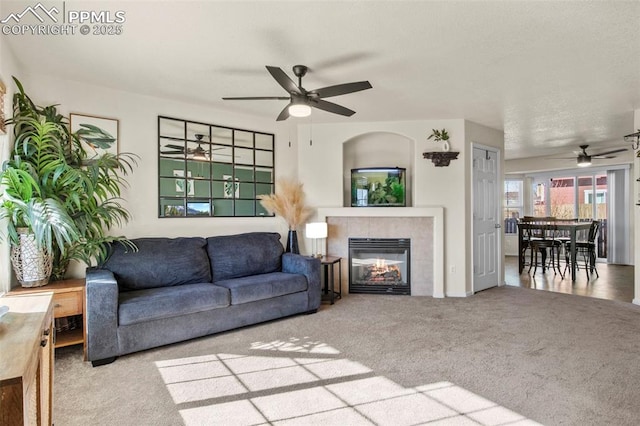 living room featuring ceiling fan, carpet, and a fireplace