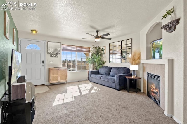 living room featuring ceiling fan, carpet flooring, and a textured ceiling