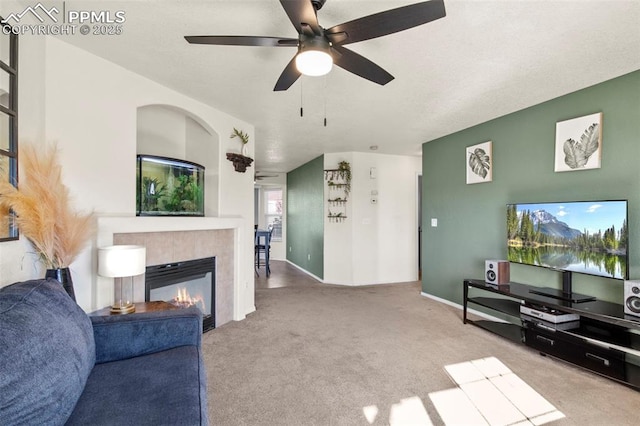 living room featuring a fireplace, light colored carpet, and ceiling fan