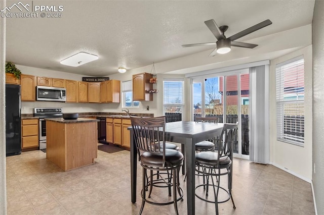 kitchen featuring a kitchen island, sink, ceiling fan, black appliances, and a textured ceiling