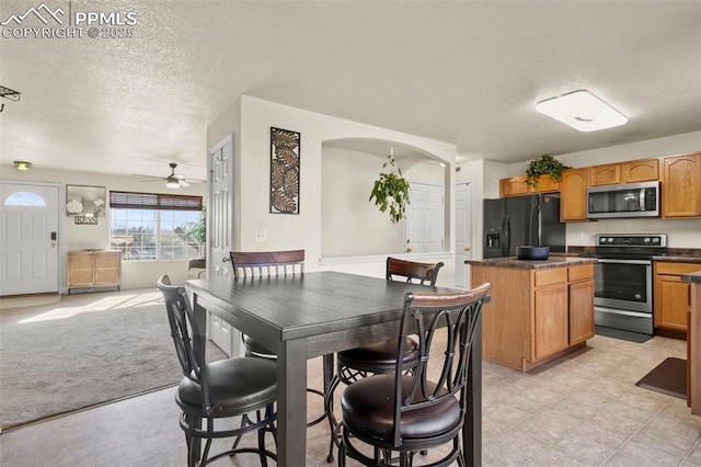 carpeted dining room with ceiling fan and a textured ceiling