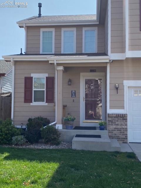 view of exterior entry with a garage and a lawn