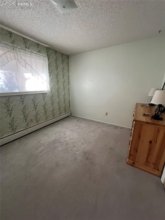 carpeted empty room with a textured ceiling and baseboard heating