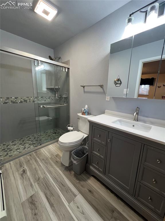 bathroom with hardwood / wood-style flooring, vanity, an enclosed shower, and toilet