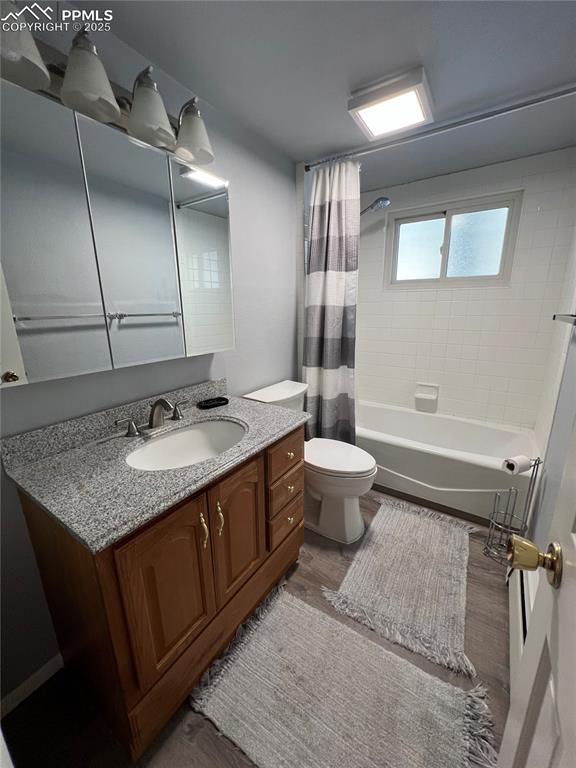 full bathroom featuring vanity, wood-type flooring, toilet, and shower / bath combo with shower curtain