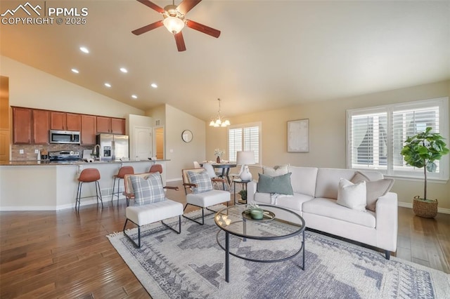 living room featuring ceiling fan with notable chandelier, dark wood-type flooring, high vaulted ceiling, and a healthy amount of sunlight