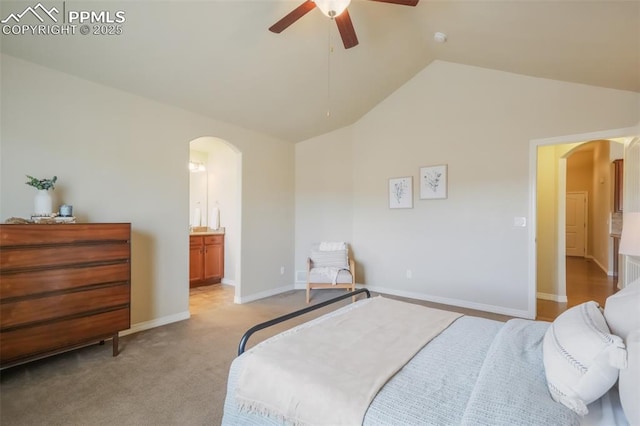 bedroom featuring vaulted ceiling, light carpet, ensuite bathroom, and ceiling fan