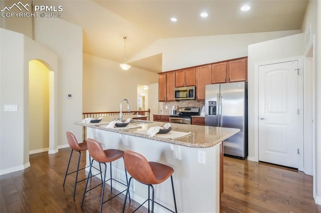 kitchen featuring dark hardwood / wood-style floors, a breakfast bar area, an island with sink, and appliances with stainless steel finishes