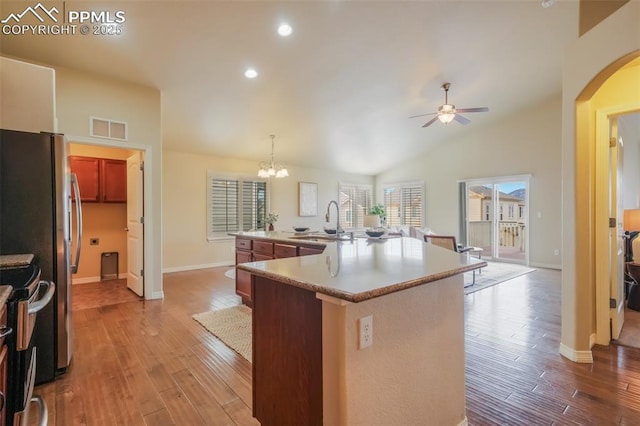 kitchen with sink, appliances with stainless steel finishes, hanging light fixtures, light hardwood / wood-style floors, and an island with sink