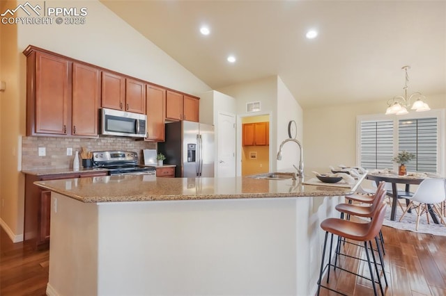 kitchen with an island with sink, appliances with stainless steel finishes, sink, and lofted ceiling