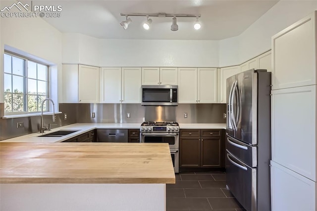 kitchen with sink, wooden counters, appliances with stainless steel finishes, kitchen peninsula, and white cabinets