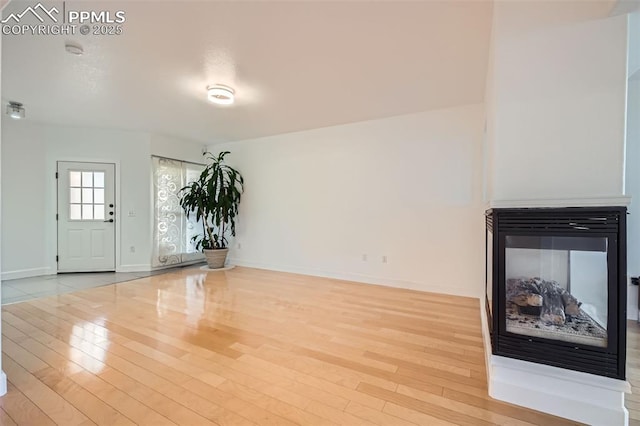 unfurnished living room with light hardwood / wood-style flooring and a multi sided fireplace