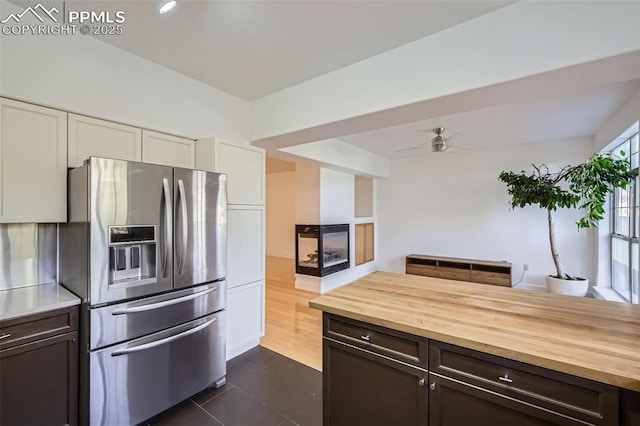 kitchen with dark tile patterned floors, white cabinets, butcher block countertops, and stainless steel fridge with ice dispenser