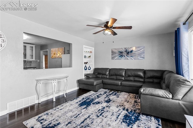 living room featuring built in shelves, dark hardwood / wood-style floors, and ceiling fan