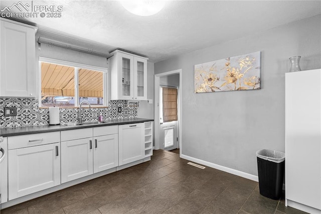 kitchen with dishwasher, white cabinetry, sink, and decorative backsplash