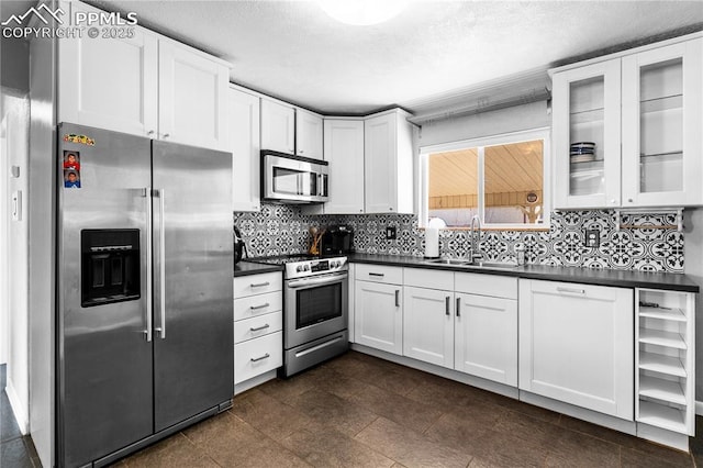 kitchen featuring sink, decorative backsplash, stainless steel appliances, and white cabinets