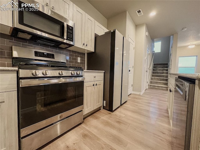 kitchen featuring white cabinetry, decorative backsplash, stainless steel appliances, and light hardwood / wood-style flooring