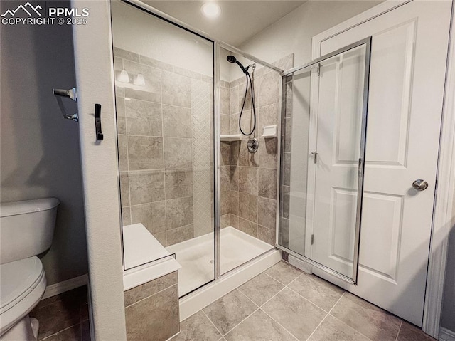 bathroom with tile patterned flooring, walk in shower, and toilet