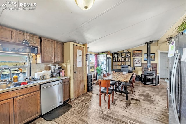 kitchen with stainless steel appliances, lofted ceiling, light wood-type flooring, and a sink