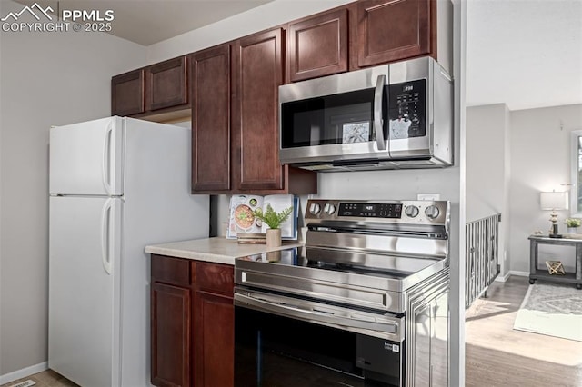 kitchen with light hardwood / wood-style flooring and appliances with stainless steel finishes