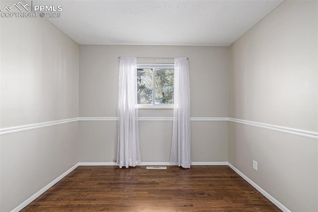 spare room featuring dark hardwood / wood-style flooring and a textured ceiling