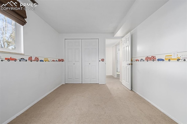 unfurnished bedroom with light carpet and a closet