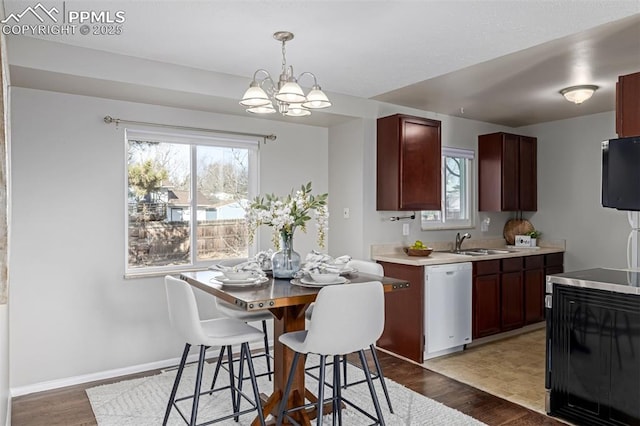 kitchen with a healthy amount of sunlight, sink, dishwashing machine, and decorative light fixtures